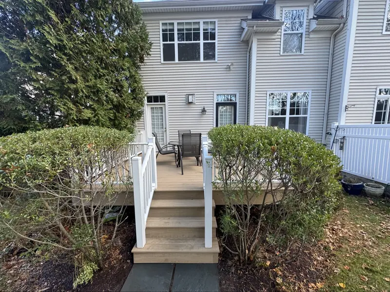 Finished deck with white railings, stairs, and patio furniture